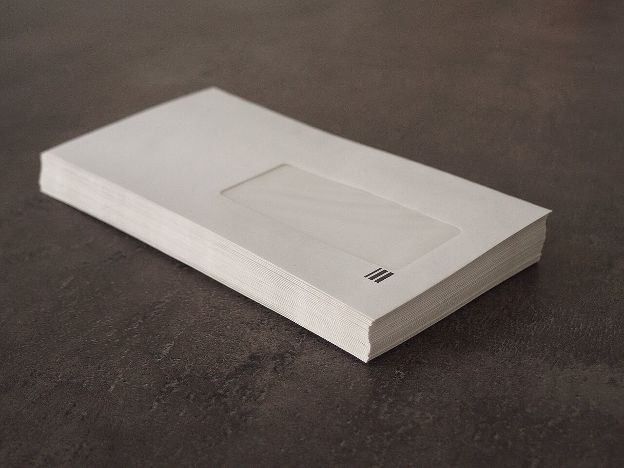 A stack of window envelopes on a dark surface